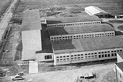 Die Betriebsberufsschule vom Hochhaus aus aufgenommen. Das Umfeld lässte noch die Bausstelle der BBS erkennen. Rechts am Gebäude sind die drei Hallen für die berufspraktische Ausbildung zu sehen.